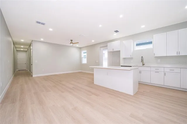 a large kitchen with stainless steel appliances a large counter top a stove a sink and a refrigerator