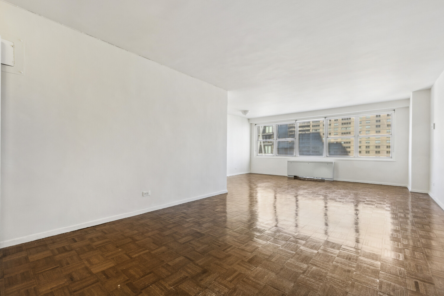 155 West 68th Street, Unit 1807 Manhattan, NY 10023 - Photo 1 of 7 an empty room with wooden floor and windows