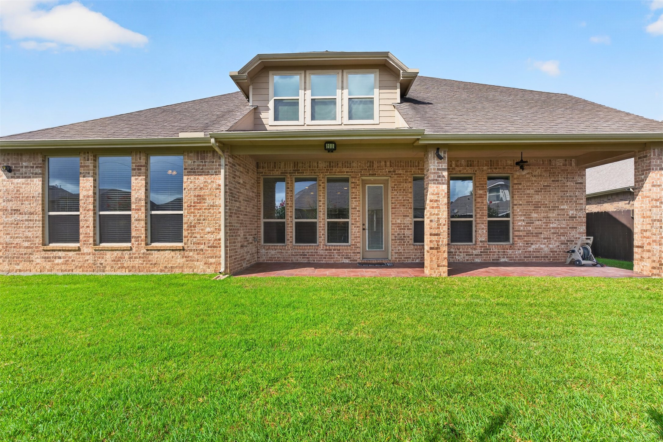 18202 Wedgewood Bluff Court Spring, TX 77379 - Photo 46 of 50 Rear exterior view with brick elevation, covered patio area, and backyard windows.