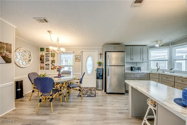 a kitchen with a refrigerator a stove top oven a sink dishwasher a dining table and chairs with wooden floor