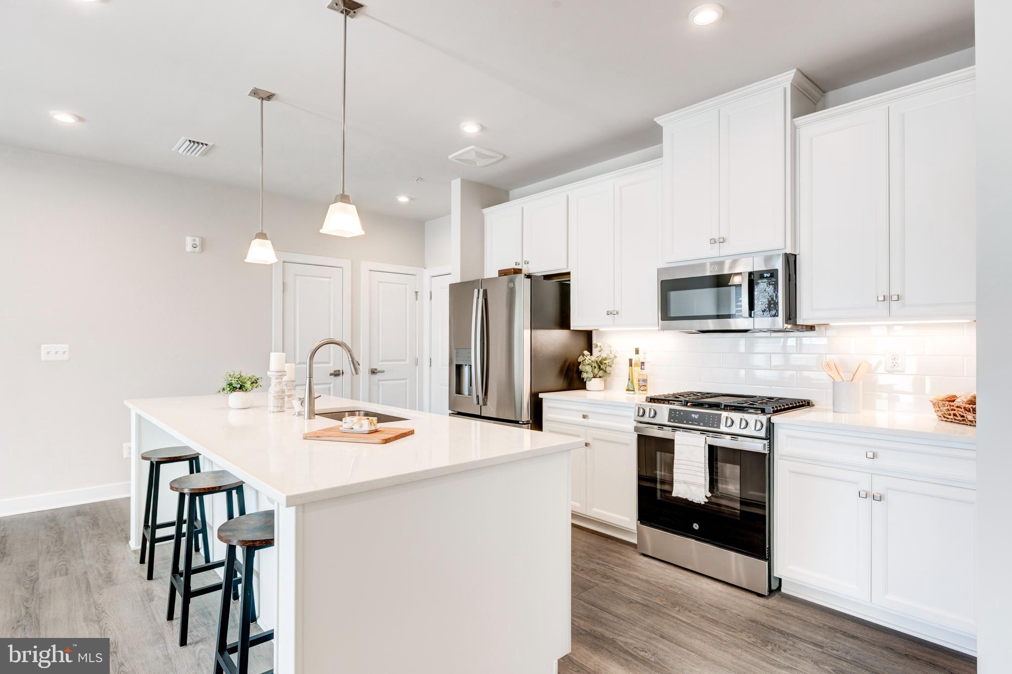 40 Liberty Road, Unit T Sykesville, MD 21784 - Photo 11 of 31 a kitchen with stainless steel appliances kitchen island a table chairs microwave and stove a refrigerator
