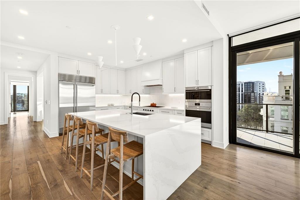 2520 Peachtree Road Northwest, Unit 1003 Atlanta, GA 30305 - Photo 1 of 63 a kitchen with stainless steel appliances kitchen island granite countertop a stove a refrigerator a sink a dining table and chairs with wooden floor