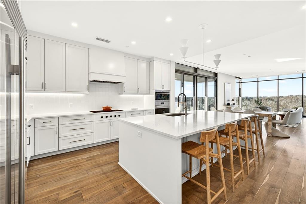 2520 Peachtree Road Northwest, Unit 1003 Atlanta, GA 30305 - Photo 5 of 63 a kitchen with stainless steel appliances kitchen island granite countertop a stove a sink and white cabinets with wooden floors
