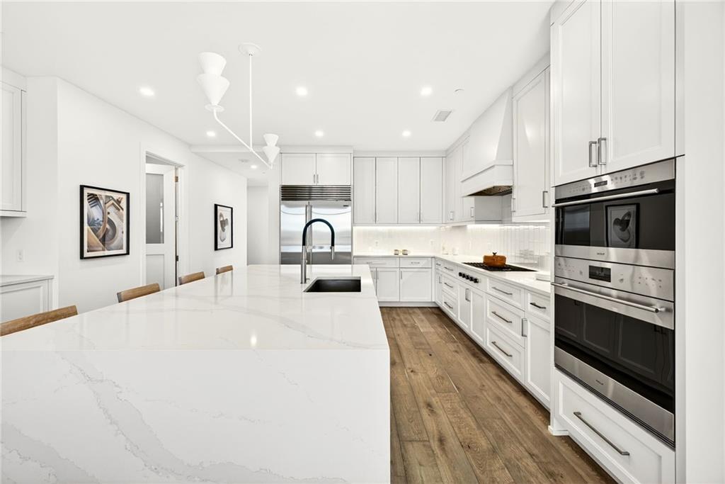 2520 Peachtree Road Northwest, Unit 1003 Atlanta, GA 30305 - Photo 7 of 63 a kitchen with stainless steel appliances kitchen island granite countertop a stove top oven a sink a refrigerator white cabinets and wooden floor