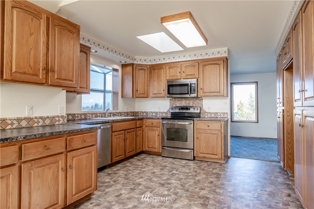 449 Guy Kelly Road Port Angeles, WA 98362 - Photo 15 of 40 a kitchen with stainless steel appliances granite countertop a stove top oven a sink dishwasher and a refrigerator with wooden cabinets