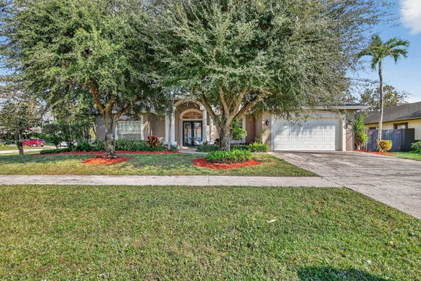 a view of the house with a backyard and trees