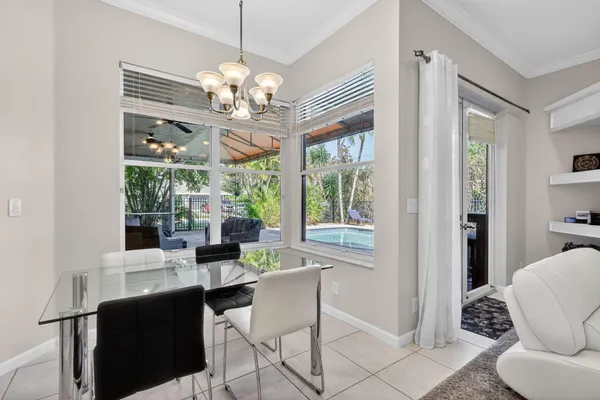 a dining room with wooden floor a chandelier a glass table and chairs