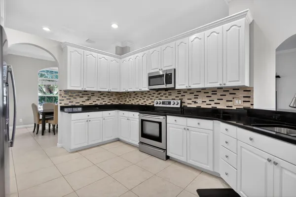 a kitchen with granite countertop white cabinets and stainless steel appliances