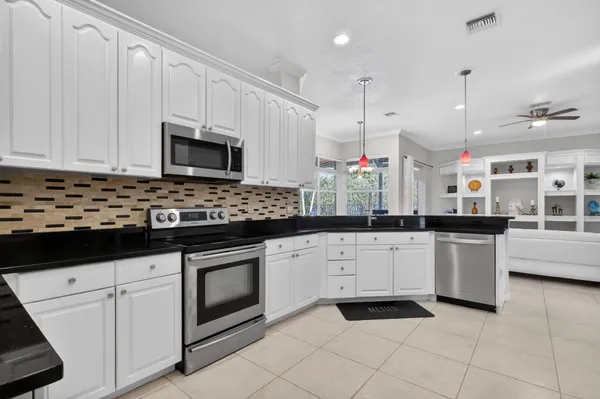 a large kitchen with a large counter top space a sink stainless steel appliances and cabinets