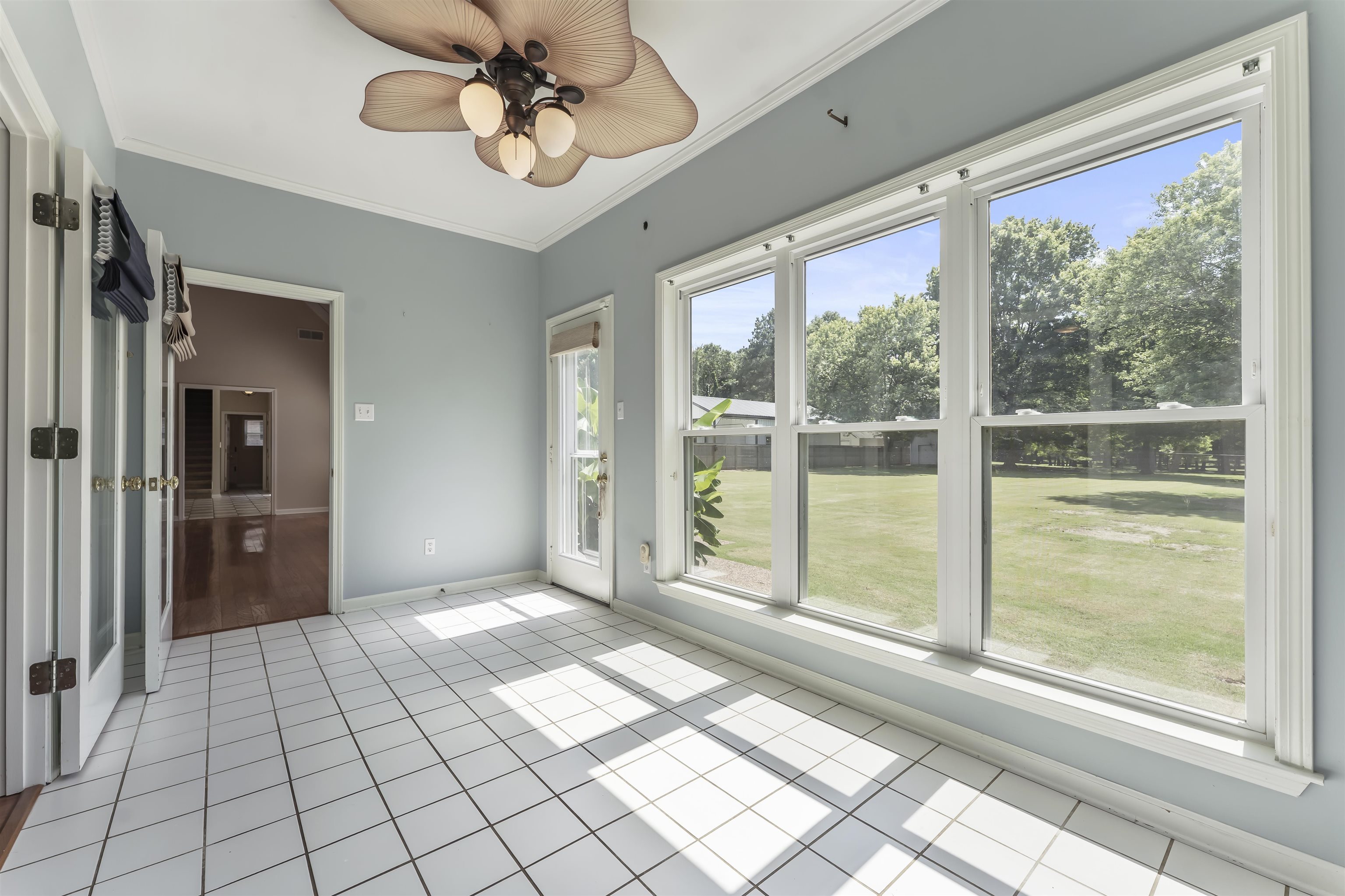 4279 High Plains Road Bartlett, TN 38135 - Photo 18 of 37 Spacious room featuring large windows, a full-light exterior door, white square tile flooring, and a ceiling fan with light fixture