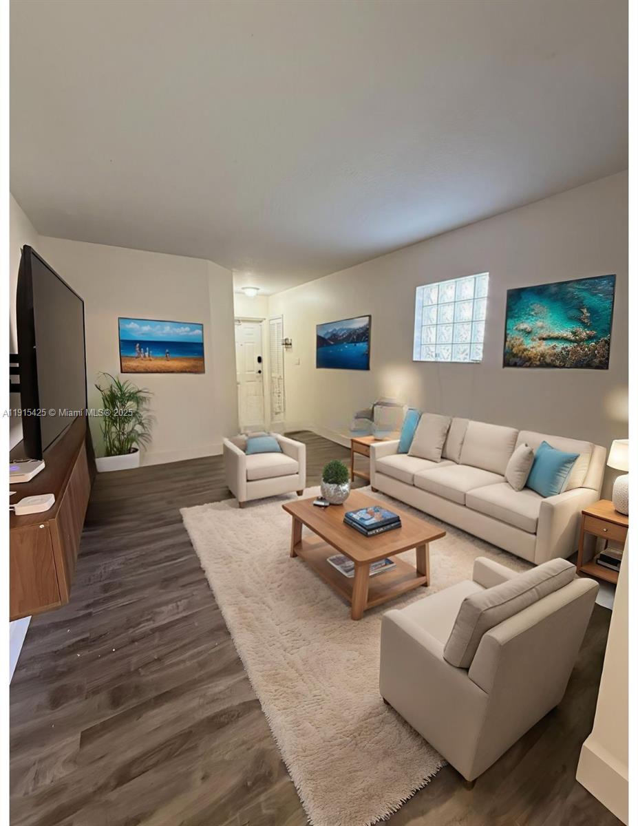 22901 Southwest 88th Place, Unit 101 Cutler Bay, FL 33190 - Photo 2 of 6 a living room with furniture a rug and a flat screen tv