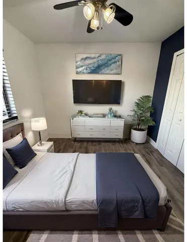 a bedroom with a bed wooden floor and couch