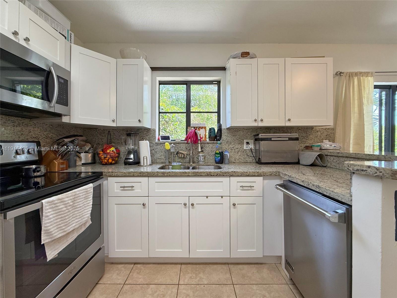 22901 Southwest 88th Place, Unit 101 Cutler Bay, FL 33190 - Photo 6 of 6 a kitchen with cabinets appliances a sink and a counter top space