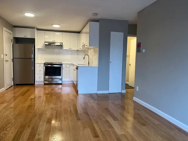 a view of kitchen with stainless steel appliances wooden floor and chair