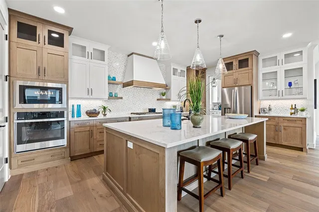 a kitchen with a sink a center island stainless steel appliances and cabinets