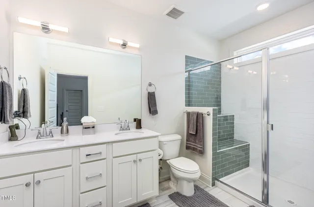 a bathroom with a double vanity sink toilet and shower