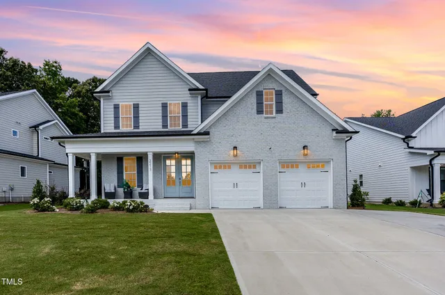 a view of a white house with a small yard and a large tree
