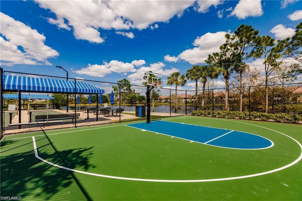 20117 Seadale Court Estero, FL 33928 - Photo 28 of 34 Outdoor basketball court with a green and blue surface, adjacent to a shaded picnic area featuring striped awnings and picnic tables