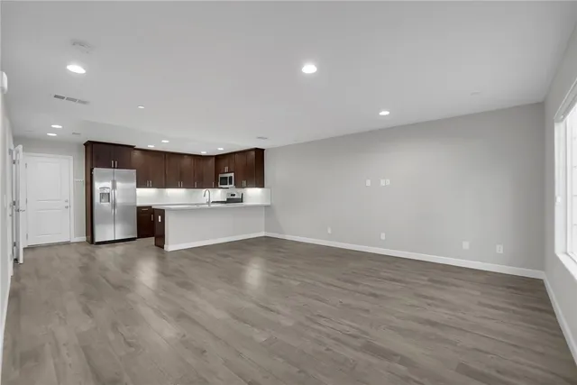 a large kitchen with stainless steel appliances a large counter top a refrigerator a sink and a stove