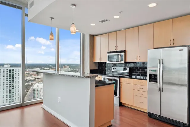 a living room with stainless steel appliances furniture and a view of kitchen