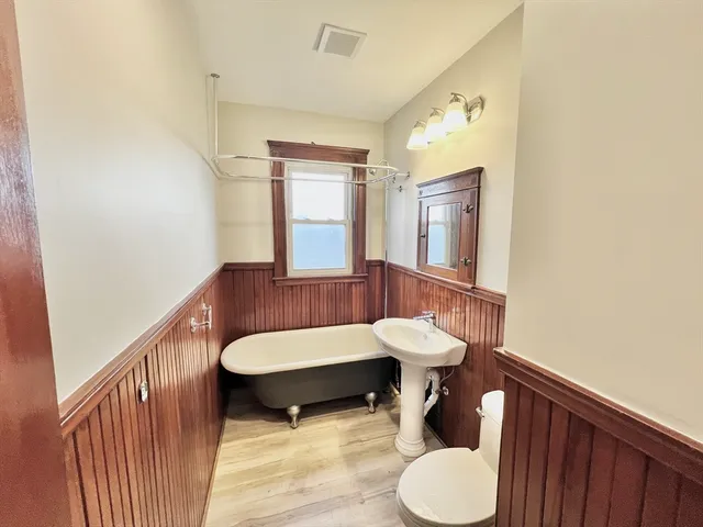 a bathroom with a tub sink and mirror