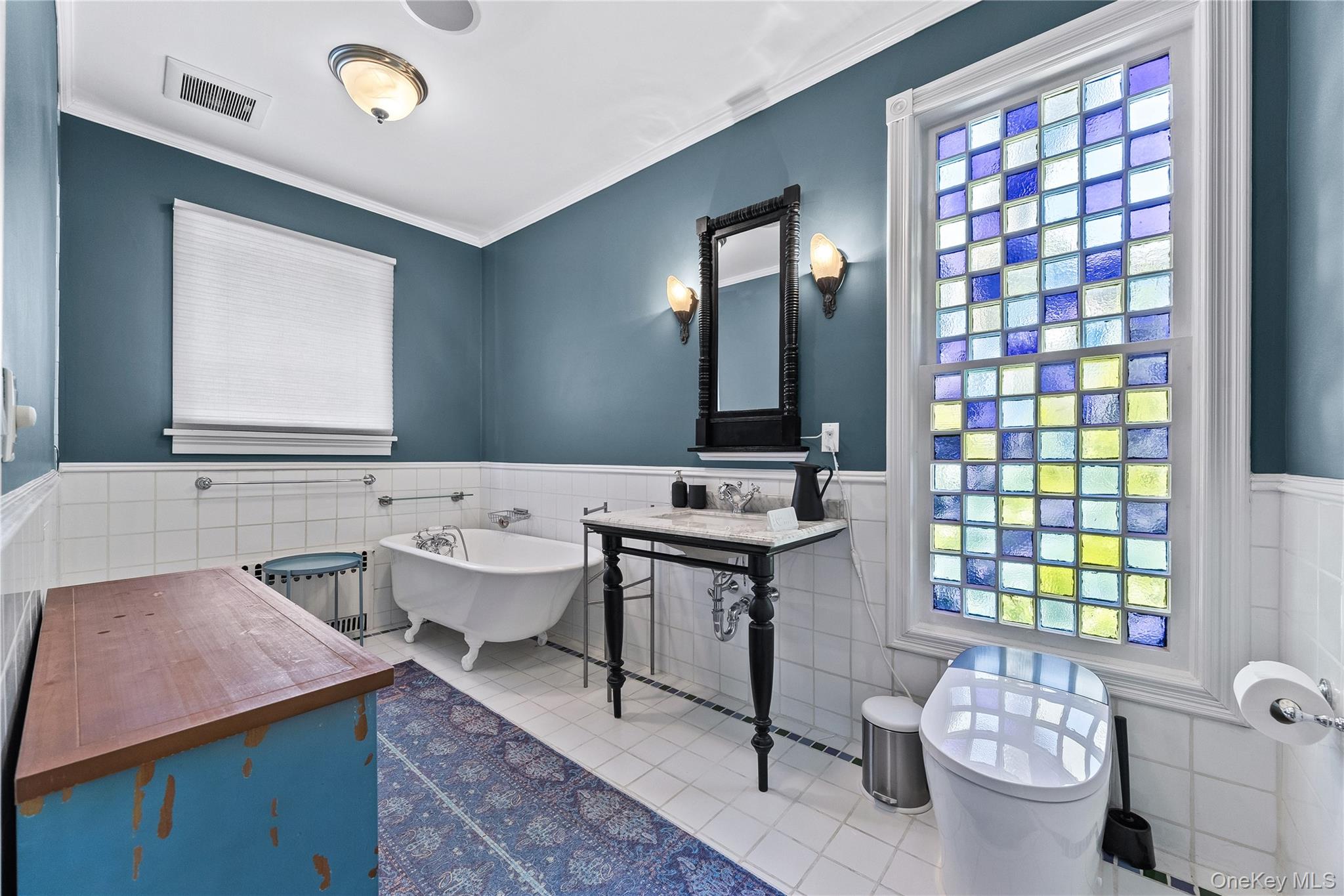 19 Howe Place Bronxville, NY 10708 - Photo 20 of 37 Bathroom featuring a colorful glass block window, clawfoot tub, white tile flooring, and a pedestal vanity with a marble top