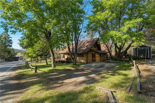 a view of a house with a yard and large trees
