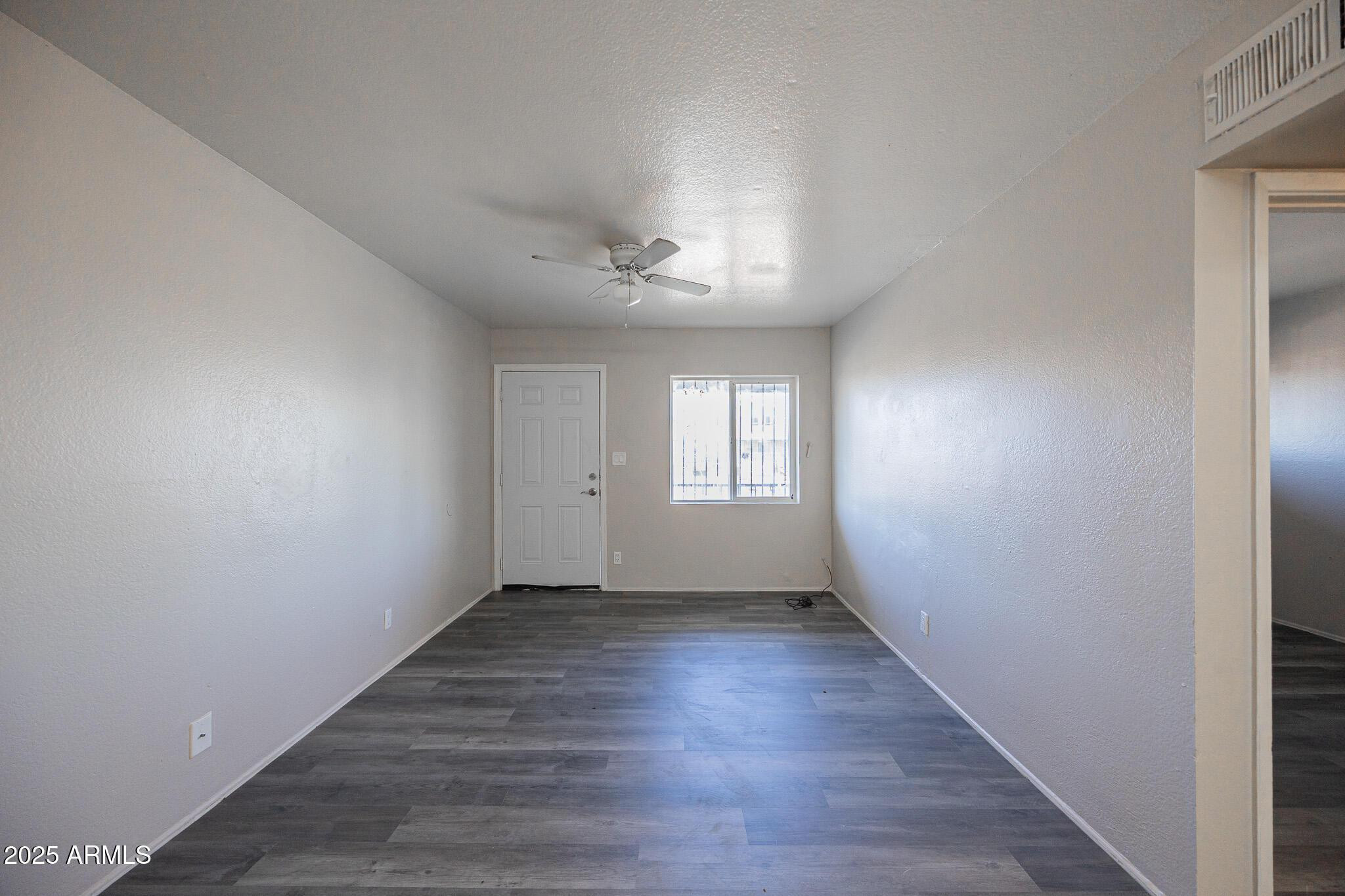 1703 West Mountain View Road, Unit 14 Phoenix, AZ 85021 - Photo 8 of 14 a view of an empty room with a window and wooden floor