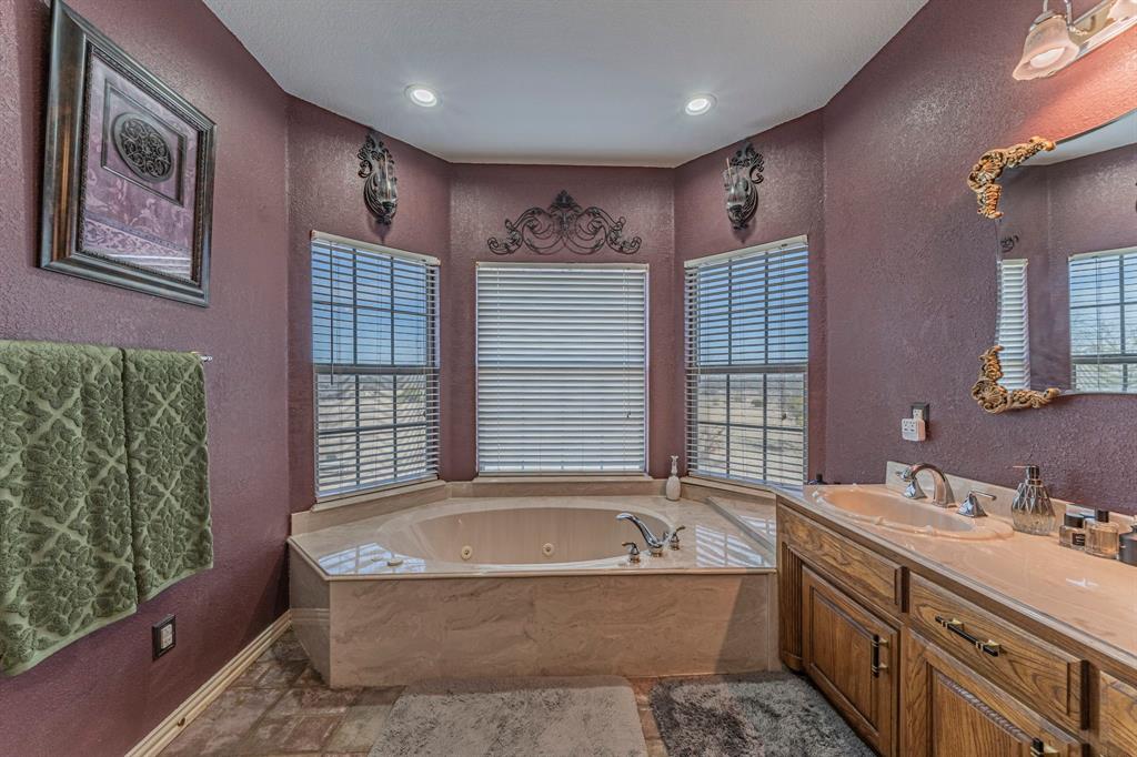 6438 Farm To Market 4 Godley, TX 76044 - Photo 16 of 32 a spacious bathroom with a granite countertop tub sink a mirror a vanity and a shower