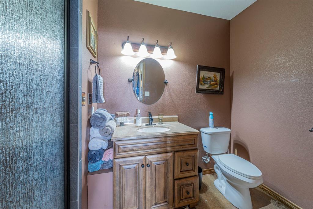 6438 Farm To Market 4 Godley, TX 76044 - Photo 19 of 32 a bathroom with a toilet sink vanity and mirror