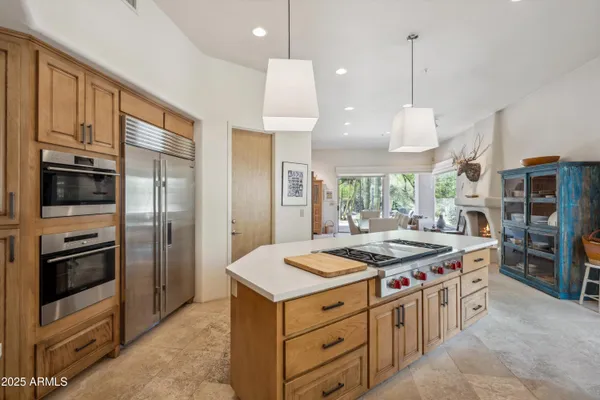 a kitchen that has a stove a kitchen island a sink stainless steel appliances and cabinets
