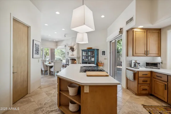 a kitchen with stainless steel appliances kitchen island granite countertop a table chairs sink and cabinets