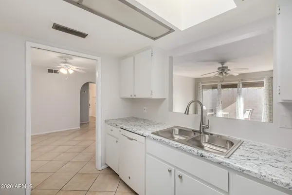a kitchen with granite countertop a sink stainless steel appliances and white cabinets
