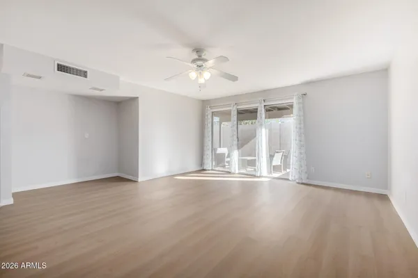 a view of an empty room with wooden floor and a window