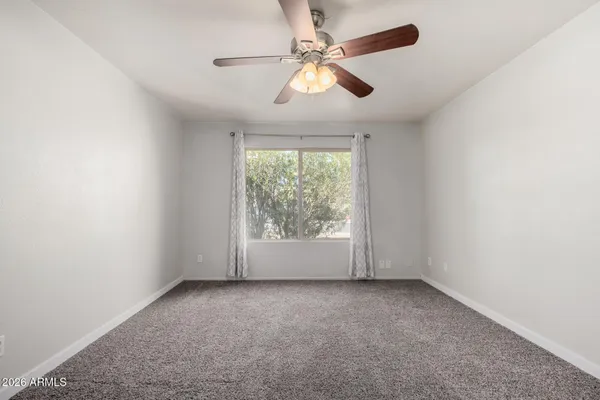 an empty room with windows and chandelier fan
