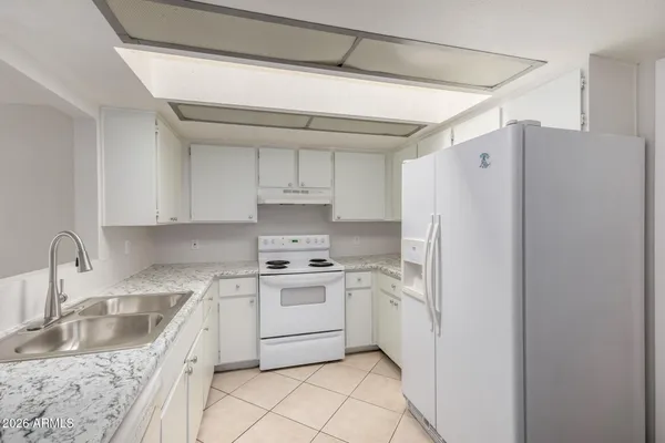 a kitchen with stainless steel appliances granite countertop a sink a stove a refrigerator and white cabinets