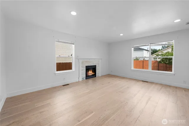 an empty room with windows and fireplace