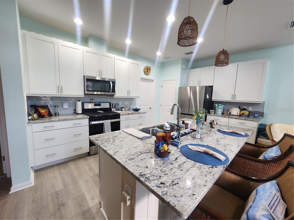 218 Ocean Hammock Loop Daytona Beach, FL 32124 - Photo 5 of 13 a kitchen with stainless steel appliances granite countertop a sink dishwasher refrigerator stove and microwave with wooden floor