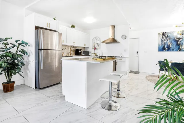 a kitchen with stainless steel appliances granite countertop a refrigerator a stove a sink dishwasher and white cabinets with wooden floor