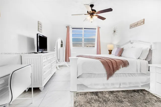 a spacious bedroom with a bed a flat screen tv and a window