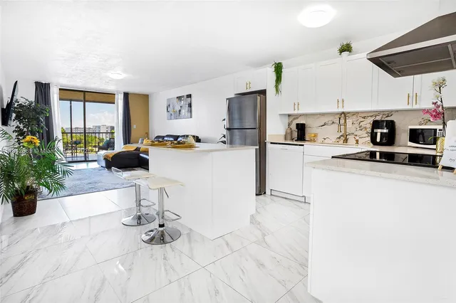 a kitchen with stainless steel appliances kitchen island granite countertop a refrigerator a stove a sink dishwasher and white cabinets with wooden floor