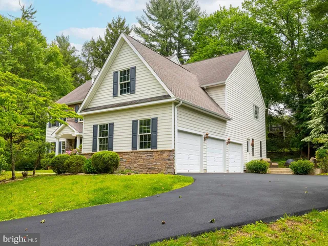 a view of a yard in front of a house with plants and large tree