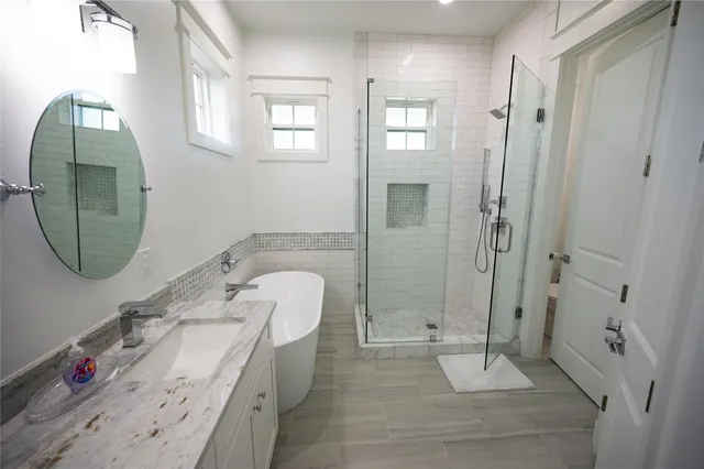 a spacious bathroom with a tub sink and mirror