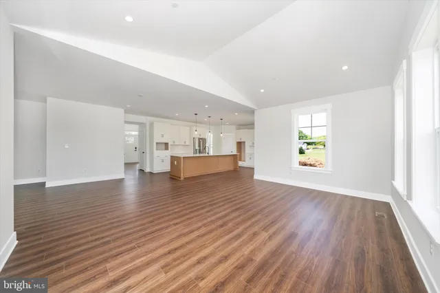 a view of empty room with kitchen and wooden floor