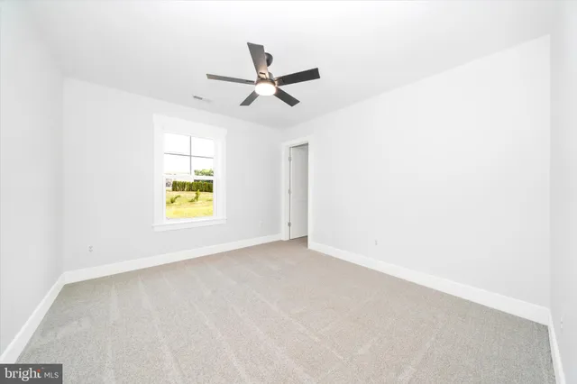 an empty room with a window and ceiling fan