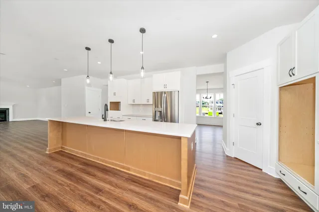 a kitchen with stainless steel appliances granite countertop a refrigerator a sink a stove and a wooden floors