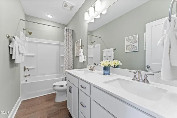 a bathroom with a double vanity sink toilet mirror and shower