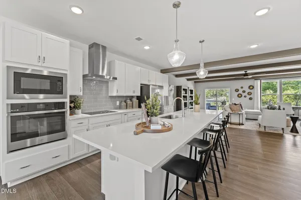 a kitchen with stainless steel appliances granite countertop a stove a microwave a dining table and chairs with wooden floor