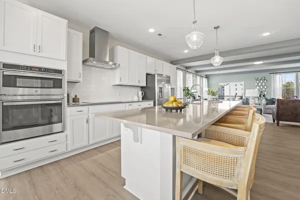 a kitchen with stainless steel appliances granite countertop a stove top oven a sink dishwasher and white cabinets with wooden floor