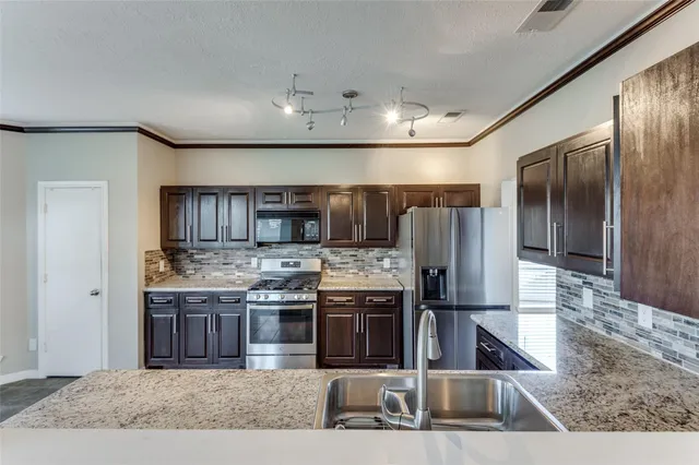 a kitchen with stainless steel appliances granite countertop a sink and a refrigerator